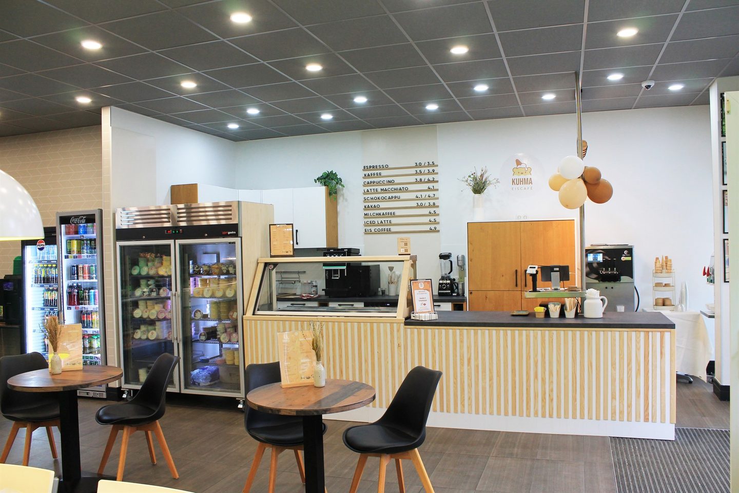Innenraum des Kuhma Eiscafés mit Eistheke, Kaffeemaschinen und Sitzplätzen